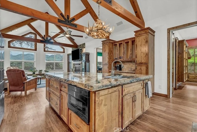 kitchen with beamed ceiling, high vaulted ceiling, a sink, and ceiling fan with notable chandelier