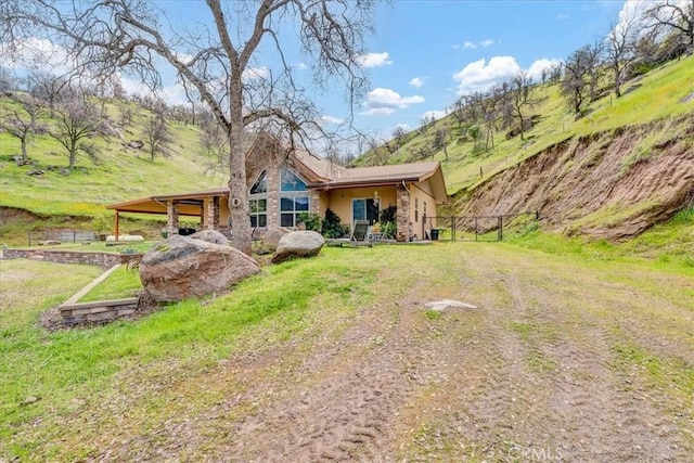 back of property featuring a yard, fence, stucco siding, and stone siding