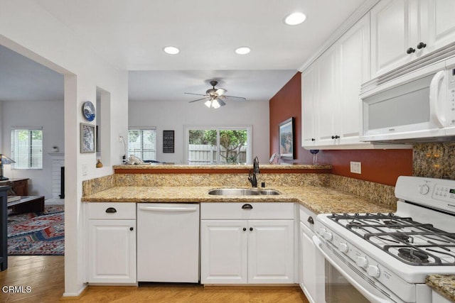 kitchen with white appliances, plenty of natural light, ceiling fan, and a sink