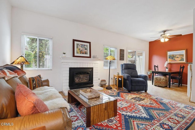 carpeted living area with a fireplace and ceiling fan