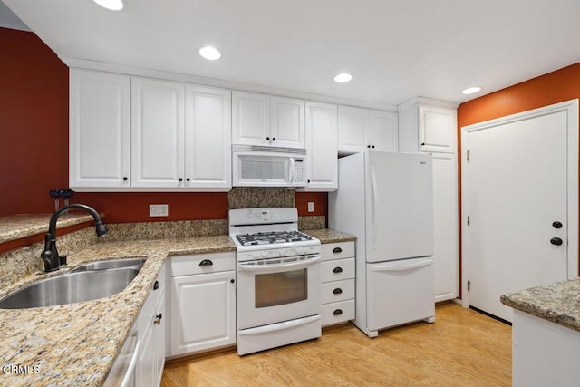 kitchen with a sink, white appliances, light wood-type flooring, and white cabinets