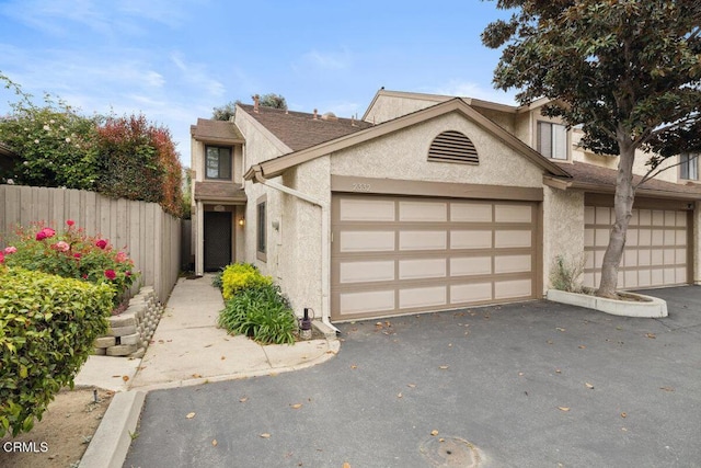view of front of home with stucco siding, aphalt driveway, a garage, and fence