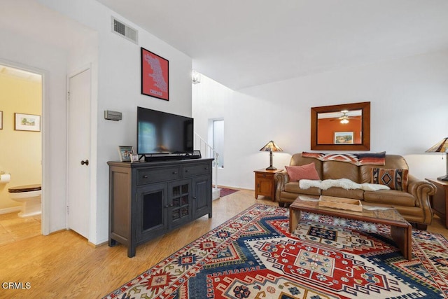 living room with light wood-style floors, visible vents, and a ceiling fan