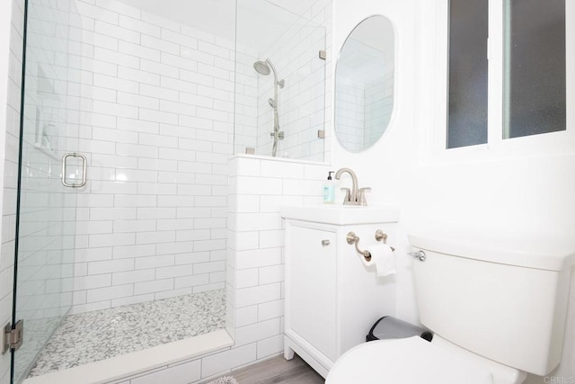 full bathroom featuring a stall shower, vanity, toilet, and wood finished floors