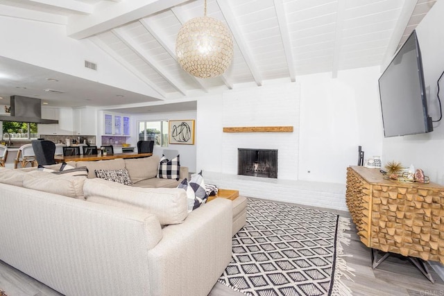 living room featuring lofted ceiling with beams, a notable chandelier, a wealth of natural light, visible vents, and light wood-style floors