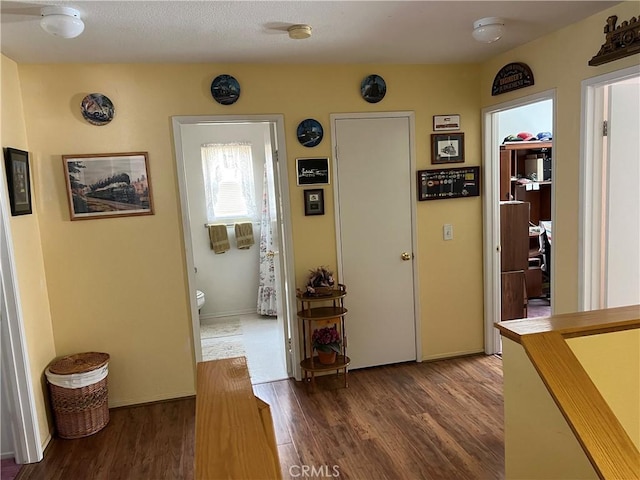 corridor featuring baseboards and dark wood finished floors