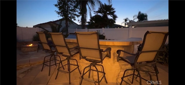 view of patio featuring an outdoor fire pit, fence, and outdoor dry bar