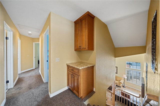 hallway featuring dark colored carpet and baseboards