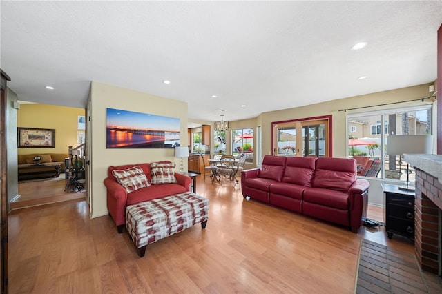 living area with light wood-style flooring, a brick fireplace, and recessed lighting