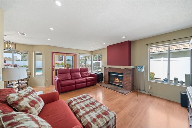 living room featuring recessed lighting, light wood-style floors, visible vents, and a brick fireplace
