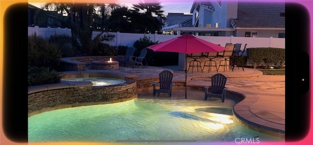 pool at dusk featuring outdoor dry bar, a patio, a fenced backyard, an in ground hot tub, and an outdoor fire pit