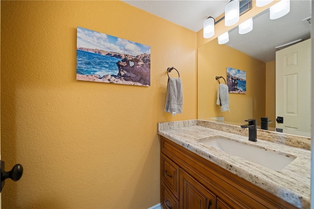 bathroom with vanity and a textured wall