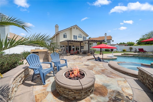 view of patio with an outdoor fire pit, a pool with connected hot tub, a ceiling fan, and a fenced backyard