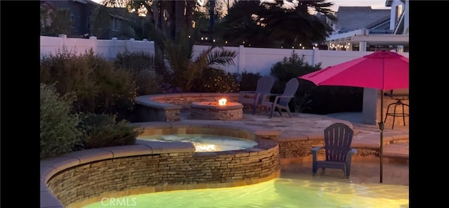 exterior space with an outdoor fire pit, a patio area, an in ground hot tub, and a fenced backyard