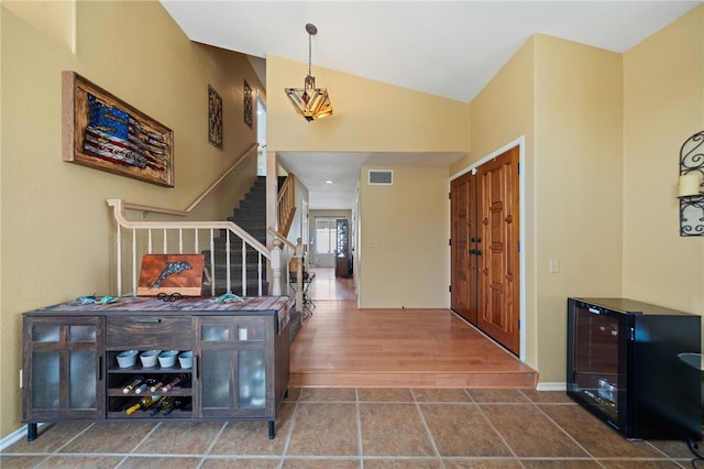 entryway with lofted ceiling, wood finished floors, visible vents, stairway, and baseboards