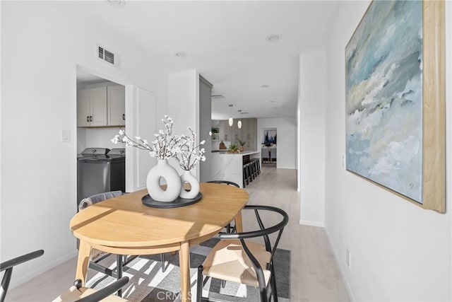 dining space featuring separate washer and dryer, visible vents, and baseboards