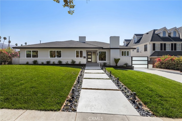 view of front of property with an attached garage, a front lawn, a chimney, and driveway