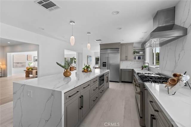 kitchen with open shelves, wall chimney exhaust hood, visible vents, built in appliances, and gray cabinetry