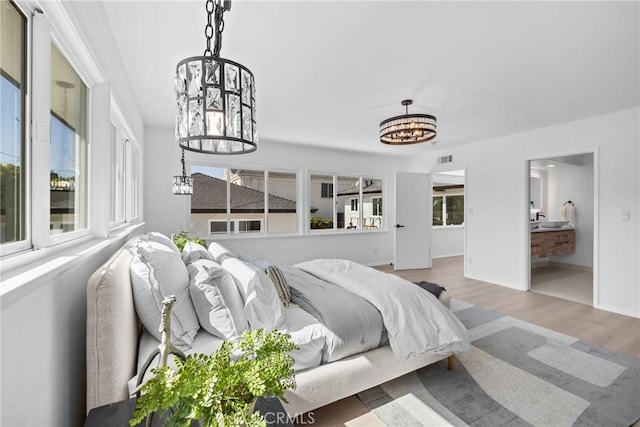 bedroom with a chandelier, wood finished floors, and visible vents