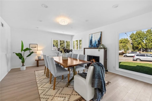 dining area with light wood-type flooring, visible vents, recessed lighting, a brick fireplace, and baseboards