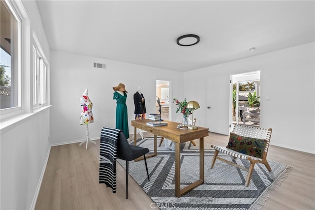 home office with visible vents, light wood-style flooring, and baseboards