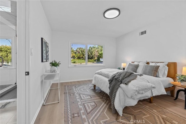 bedroom featuring baseboards, visible vents, and wood finished floors