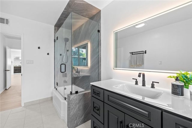 bathroom featuring vanity, visible vents, tile patterned floors, enclosed tub / shower combo, and baseboards