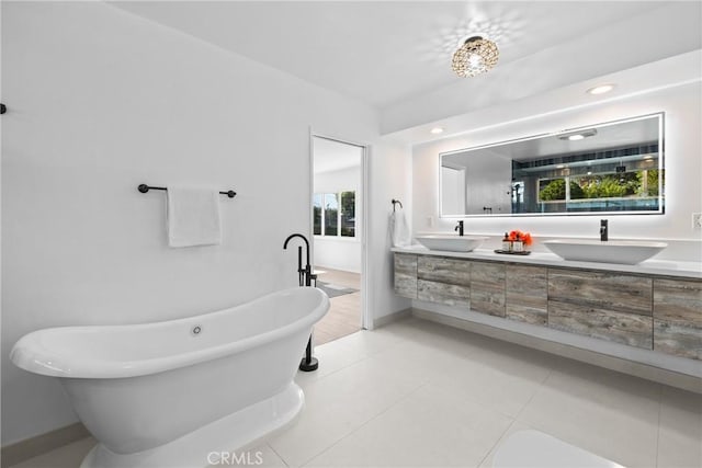 bathroom with a freestanding bath, tile patterned floors, double vanity, and a sink