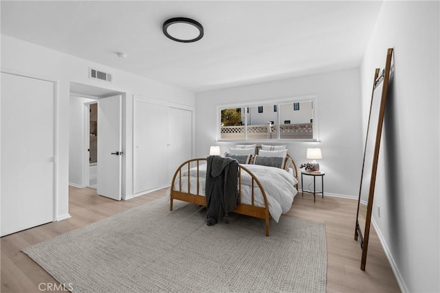 bedroom featuring a closet, baseboards, visible vents, and wood finished floors