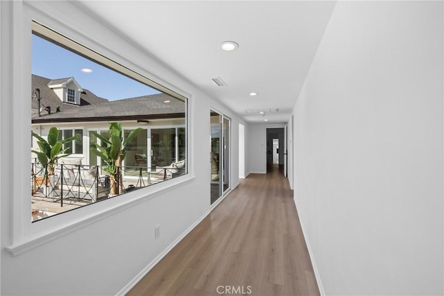 corridor featuring baseboards, recessed lighting, and wood finished floors