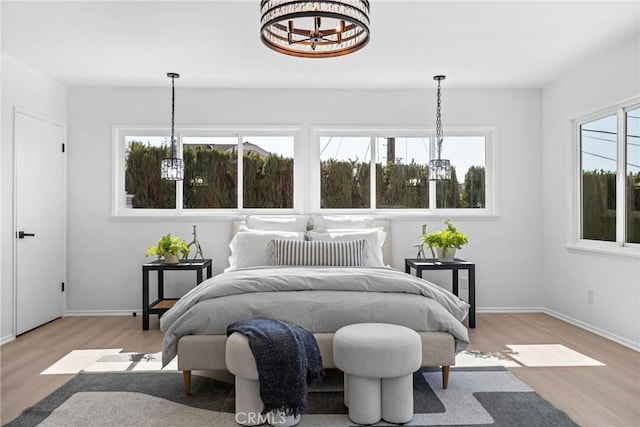 bedroom with baseboards, a notable chandelier, and wood finished floors
