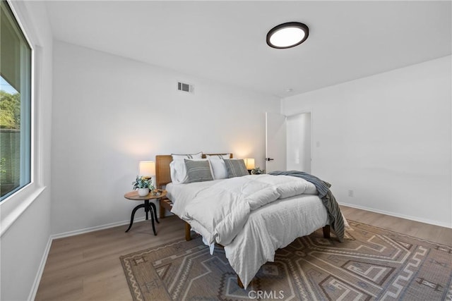 bedroom with baseboards, visible vents, and wood finished floors