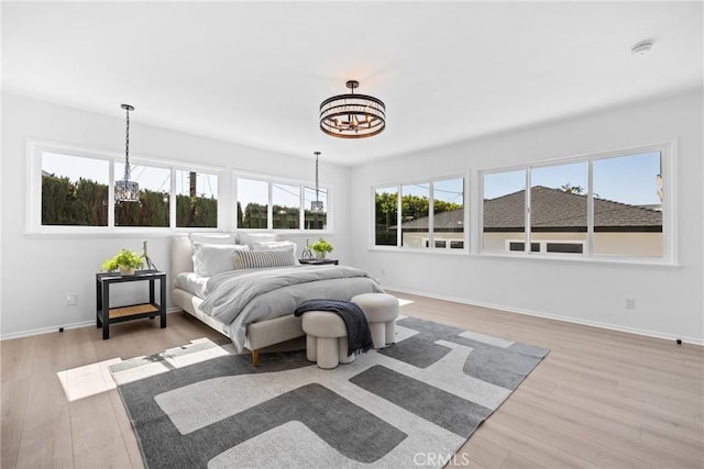bedroom with baseboards, a chandelier, and wood finished floors