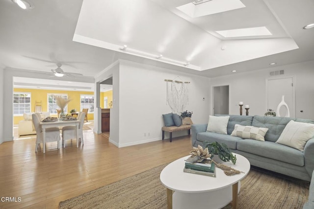 living area featuring a skylight, light wood-type flooring, visible vents, baseboards, and recessed lighting