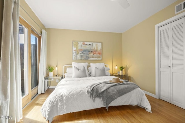 bedroom featuring a closet, light wood-type flooring, visible vents, and baseboards