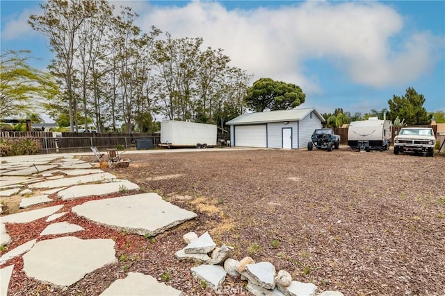 view of yard featuring fence, a garage, and an outbuilding