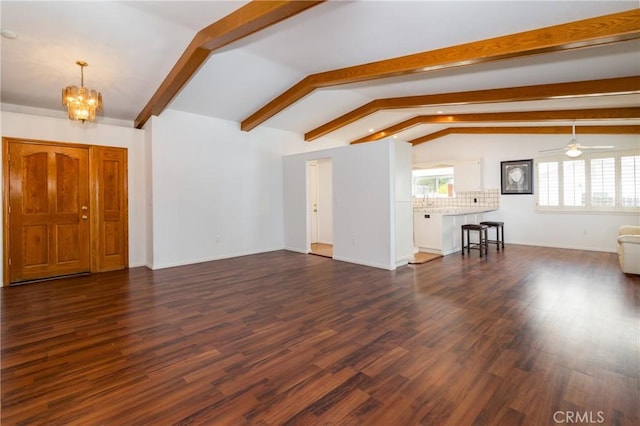 unfurnished living room with baseboards, dark wood-style flooring, ceiling fan with notable chandelier, and vaulted ceiling with beams