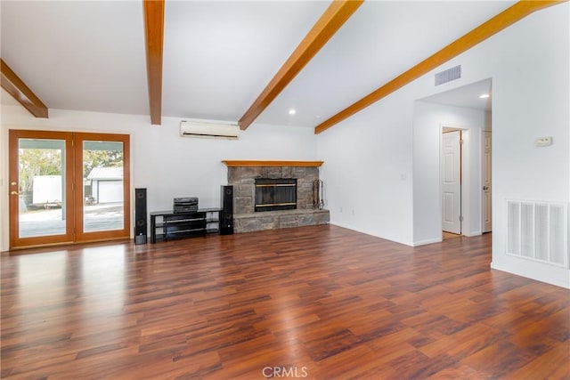 unfurnished living room featuring a fireplace, a wall mounted air conditioner, visible vents, and wood finished floors