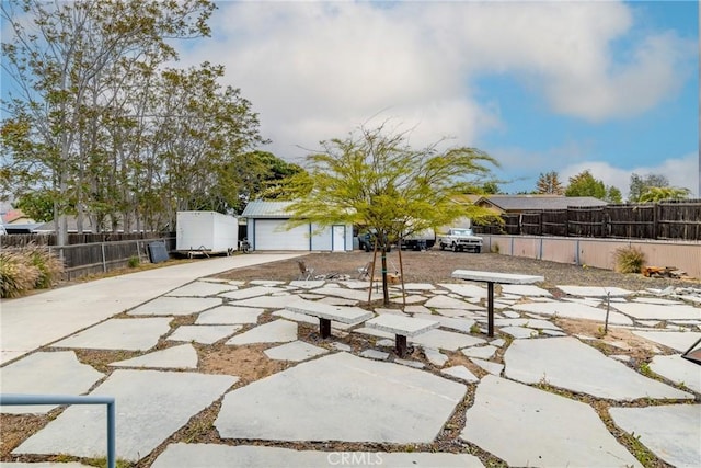 view of patio / terrace featuring concrete driveway, a garage, and fence