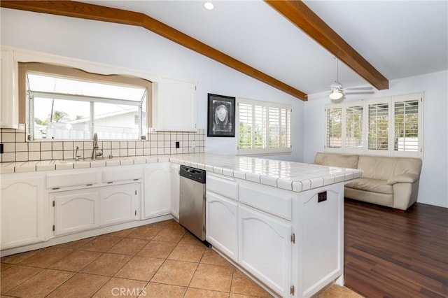 kitchen with open floor plan, a peninsula, stainless steel dishwasher, and lofted ceiling with beams