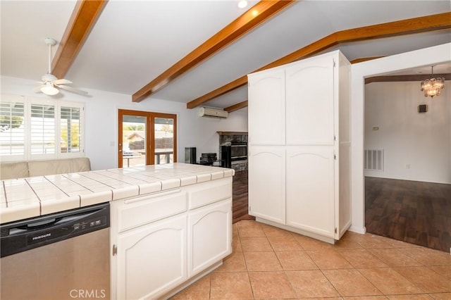 kitchen featuring lofted ceiling with beams, tile countertops, visible vents, a wall unit AC, and stainless steel dishwasher