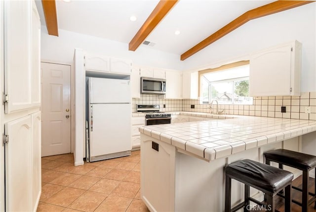 kitchen featuring a breakfast bar area, white cabinetry, a peninsula, tasteful backsplash, and appliances with stainless steel finishes