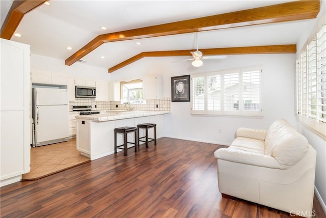 interior space featuring dark wood-style flooring, ceiling fan, a wealth of natural light, and vaulted ceiling with beams
