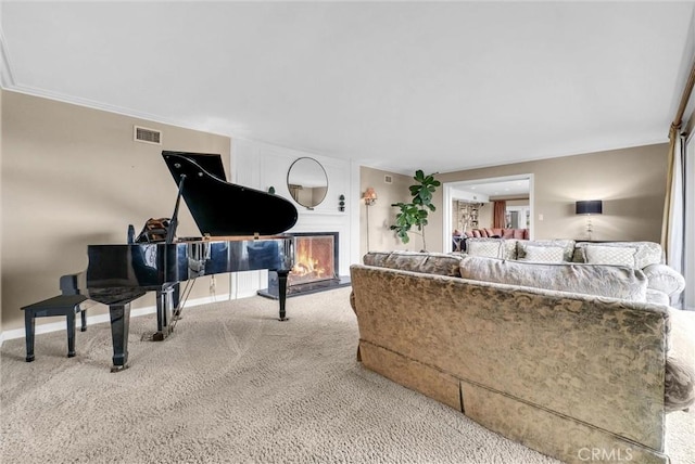 living room featuring a lit fireplace, carpet flooring, baseboards, and visible vents