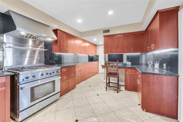kitchen with dark countertops, gas range, visible vents, wall chimney range hood, and decorative backsplash