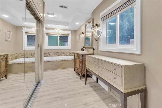full bath featuring wood finished floors, a bath, visible vents, a chandelier, and vanity