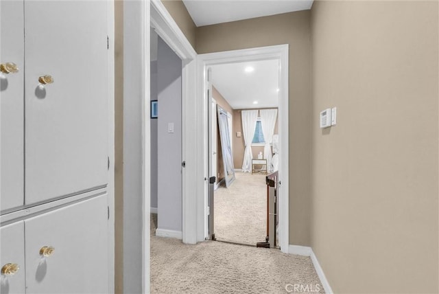 hall featuring baseboards and carpet flooring
