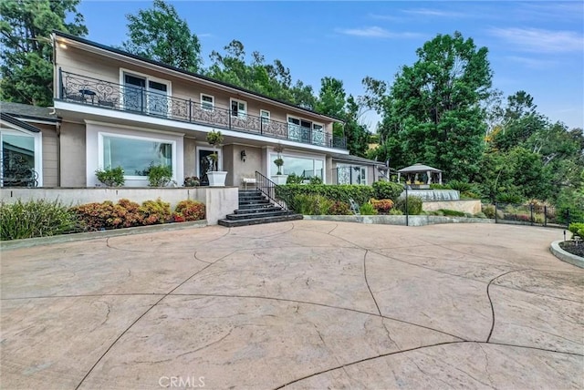 view of front of property with stucco siding, stairs, and a balcony