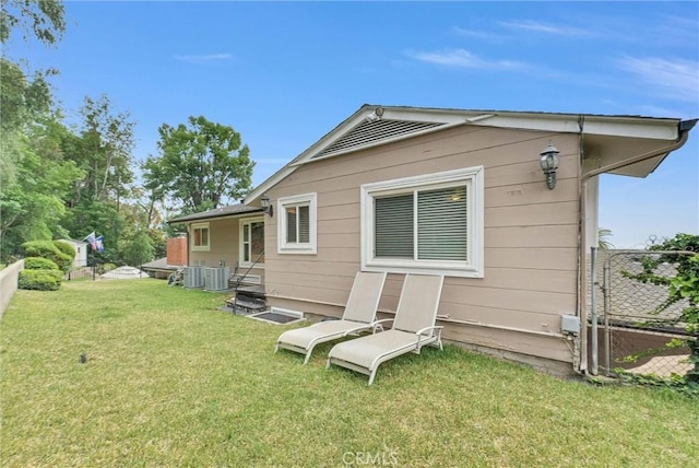 rear view of house with a yard, fence, and cooling unit