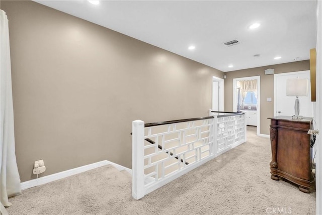hallway featuring baseboards, recessed lighting, visible vents, and light colored carpet